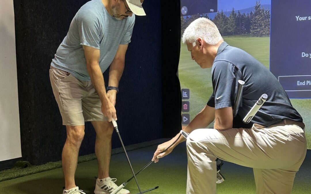 Golf club fitting at Airway Hills Golf Center in Pullman, Washington, with a golfer testing clubs while a professional analyzes swing data and equipment fit